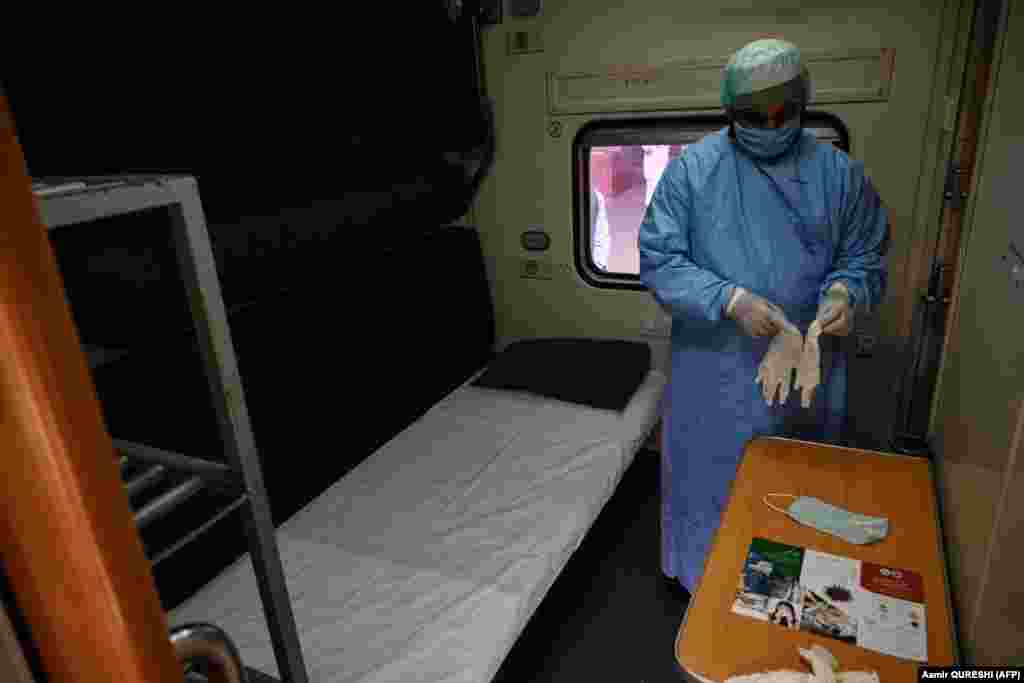 A medical worker wearing protective gear puts on gloves in a train carriage being used as a temporary quarantine facility in Rawalpindi, Pakistan.