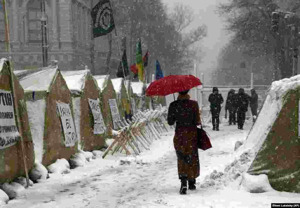 Under heavy snowfall, a woman passes by a tent camp placed by supporters of the Movement of New Forces, the political party led by Mikheil Saakashvili, in front of the parliament building in Kyiv, Ukraine. (AP/Efrem Lukatsky)