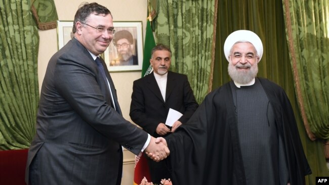 French oil giant Total Chief Executive Officer, Patrick Pouyanne (L) shakes hands with Iranian President Hassan Rohani, in Paris, January 28, 2016