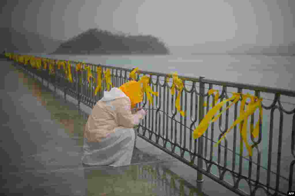 A relative of one of the hundreds of victims of the &quot;Sewol&quot; ferry disaster weeps in front of yellow ribbons at South Korea&#39;s Jindo harbor. Three hundred and two people were still dead or still missing on April 26, the majority of them schoolchildren, while 174 people survived, including 22 of 29 crew members. (AFP/Ed Jones)