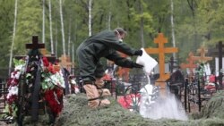 Čovjek sa zaštitnom opremom sipa bijeli prah iz vreće u grob preminulog od korona virusa tokom sahrane u Moskvi, Rusija, 26. maja 2020. godine.