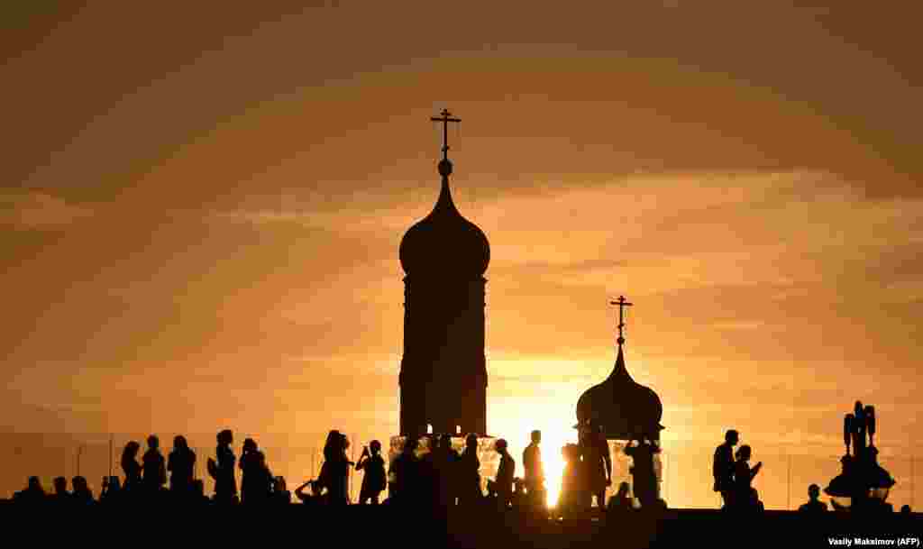 People walk along a pedestrian bridge in downtown Moscow at sunset. (AFP/Vasily Maximov)