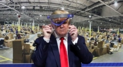 Президент США Дональд Трамп тримає захисний щит проти коронавірусу під час візиту на завод Ford Rawsonville Components, який виробляє вентилятори штучного дихання, захисні маски і щити та інше спорядження проти коронавірусу