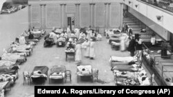 Na ovoj arhivskoj fotografiji obolelima tokom pandemije iz 1918. godine, smeštenim u bolnici u Oklandu (SAD), pomažu medicinske sestre Crvenog krsta. 