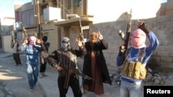 Persona të maskuar e të armatosur patrullojnë në rrugët e qytetit Falluxha në Irak