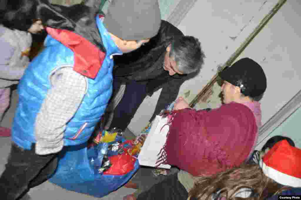 Volunteer Santas bring in bags of gifts.