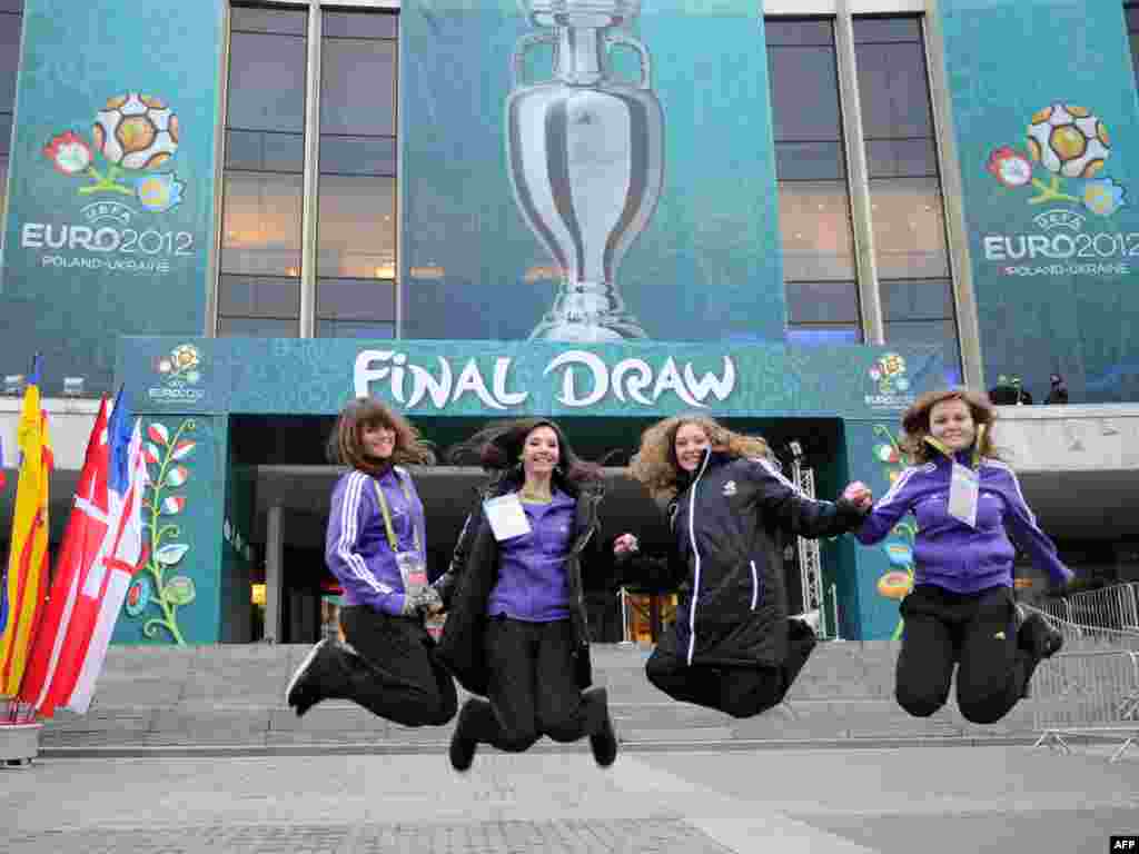 UEFA volunteers jump in front of the National Palace of Arts in Kyiv on December 1, one day ahead of the draw there for the Euro 2012 football competition, which will be hosted by Ukraine and Poland. (AFP Photo/ Franck Fife)