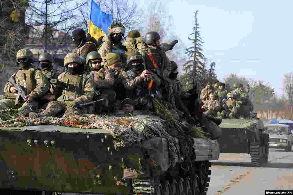 28 martie 2022, Trostineț, regiunea Sumî: Soldații ucraineni, strânși pe tancuri, trec printr-un sat.