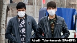 Iranians wearing face masks walk in Tehran on February 24.