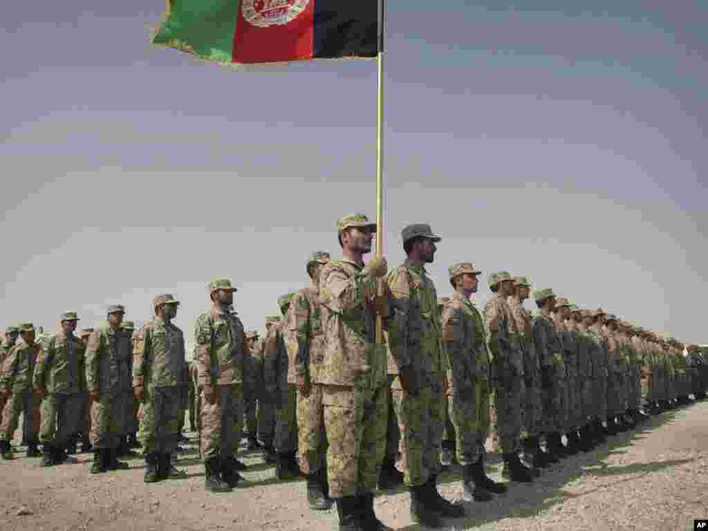An Afghan police officer holds a national flag during a graduation ceremony in Herat on August 24. Photo by Hoshan Hashimi for AP