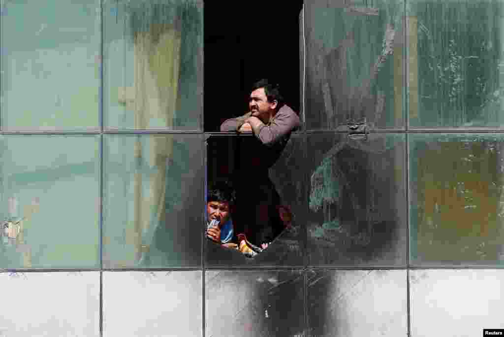 Men watch the Hazara demonstrators during the protest in Kabul, Afghanistan, on May 16. (Reuters/Mohammad Ismail)