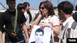 Наталья Эстемирова держит плакат "Верните Булата" на акции в поддержку сотрудника "Мемориала", пропавшего без вести в Чечне в 2007 году 