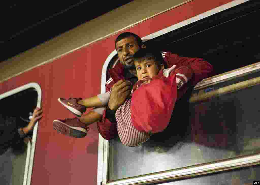 A man pulls a child into the window of a train heading to Serbia from the Macedonian-Greek border near Gevgelija. Macedonia is a key transit country in the Balkans migration route into the European Union, with thousands of asylum seekers and migrants -- many of them from Syria, Afghanistan, Iraq, and Somalia -- entering the country every day. (AFP/Robert Atanasovski)