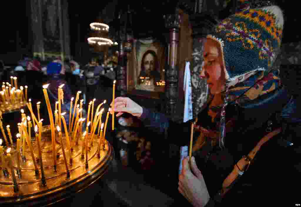 A woman lights a candle during the Orthodox Christmas Eve mass at St. Volodymir Cathedral, in the Ukrainian capital, Kyiv.