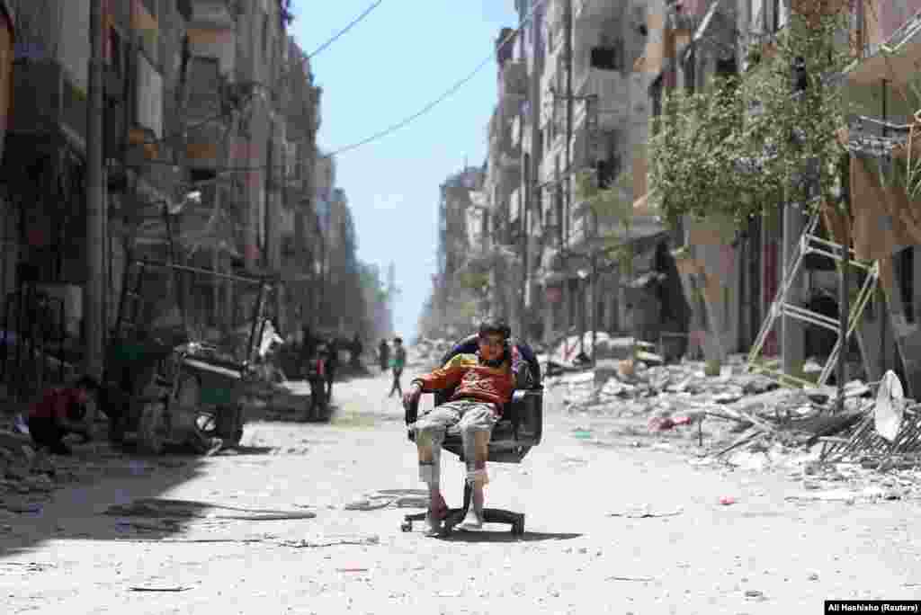 A boy sits in a chair along a damaged street at the city of Douma near Damascus, Syria. (Reuters/Ali Hashisho)