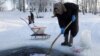 Старушка полощет белье в проруби на Сиверском озере в городке Кириллов