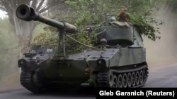 Украиналық сарбаздар америкалық соғыс техникасы – ұңғысы 155 мм болатын зеңбірегі бар М109 гаубицасын айдап бара жатыр. Донецк облысы, 13 маусым, 2022 жыл. Архивтегі фото