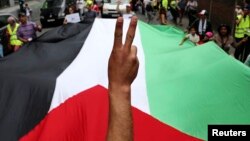 Një demonstrues bën simbolin e fitores përpara një flamuri palestinez gjatë një proteste kundër një prej aksioneve ushtarake të Izraelit në Gaza. Fotografi ilustruese nga arkivi.