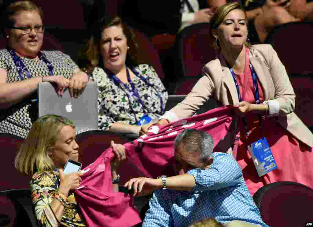 A protester with the activist group Code Pink shouts as a delegate tries to pull her banner away during the Republican National Convention in Cleveland, Ohio. She was attempting to unfurl a banner that said, "Yes We Can End War." (AFP/Dominick Reuter)