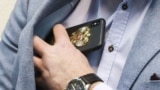 Российский чиновник кладет в карман пиджака телефон. Иллюстративное фото