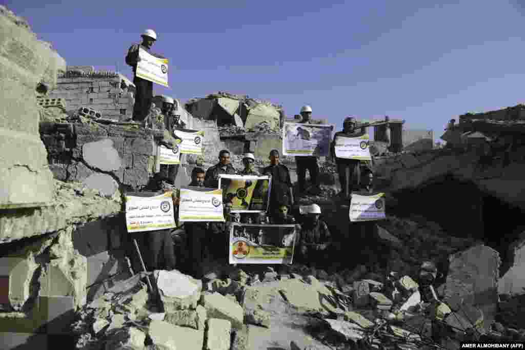Syrian Civil Defense members, also known as the White Helmets, stand in protest on August 22 on the rubble of buildings in Zamalka, near Syria's capital, Damascus, to commemorate the fourth anniversary of a reported chemical-weapons attack on the Ghouta area. (AFP/Amer Almohibany)