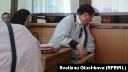 Адвокат Ермек Сыздыков (в центре) разговаривает со своим подзащитным Русланом Темербулатовым в зале суда. Астана, 13 июня 2014 года. 