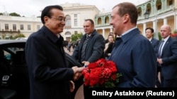 Russian Prime Minister Dmitry Medvedev (right)welcomes Chinese Premier Li Keqiang in St. Petersburg on September 16.