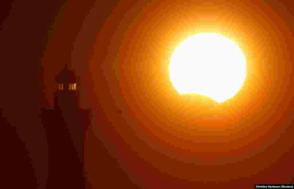 The lighthouse of Eckmuehl is seen in silhouette at sunset during a partial solar eclipse as the moon passes in front of the sun in Penmarc&#39;h, in Brittany, France, on August 21. (Reuters/Christian Hartmann)