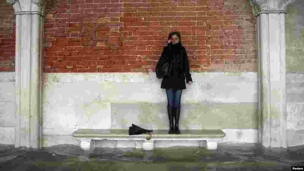 A woman stands on a bench above a flooded street during a period of seasonal high water in Venice, Italy. The water level in the canal city rose to 149 centimeters above normal. (Reuters/Manuel Silvestri)