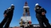 Russia - Workers look at a drilling rig at a well pad of the Rosneft-owned Prirazlomnoye oil field outside the West Siberian city of Nefteyugansk, Russia, August 4, 2016.