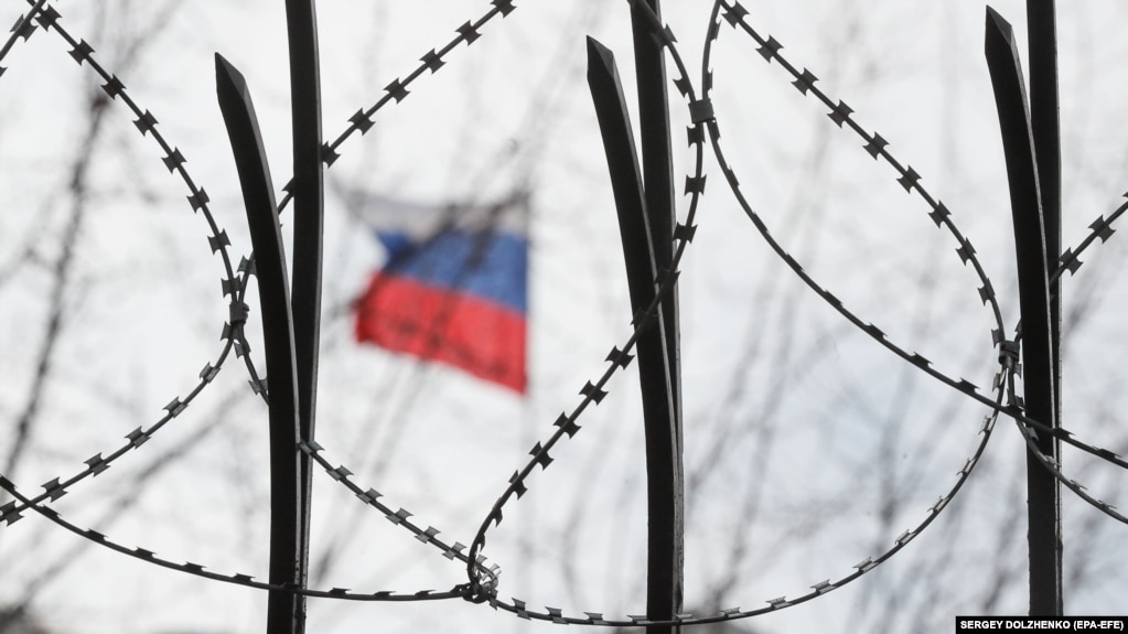 Російський прапор за колючим дротом на паркані посольства Росії в Києві