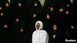 FILE PHOTO: A woman from an African Islamic country (in white) stands among Iranian women during the national anthem of Iran at the opening session of the 8th Islamic Conference Summit in Tehran's new conference building on December 9. REUTERS/Yannis Behr