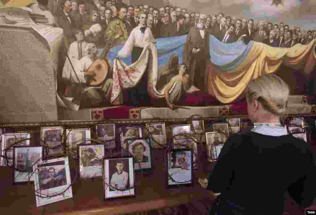 A woman looks at portraits of those who were killed during the recent unrest in Kyiv, which are dispalyed in a parliament corridor. (ITAR-TASS/Maksim Nikitin)