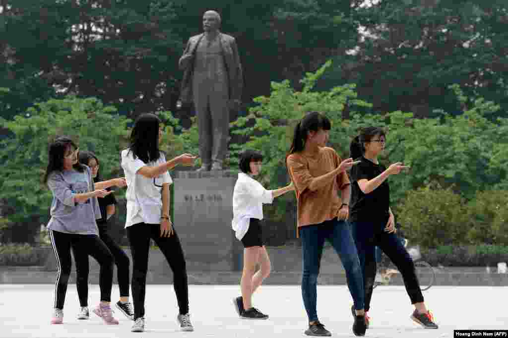 Hanoi, Vietnam: Lenin looking a little clay-footed behind the nimble-stepping youngsters practicing dance routines on Lenin square.