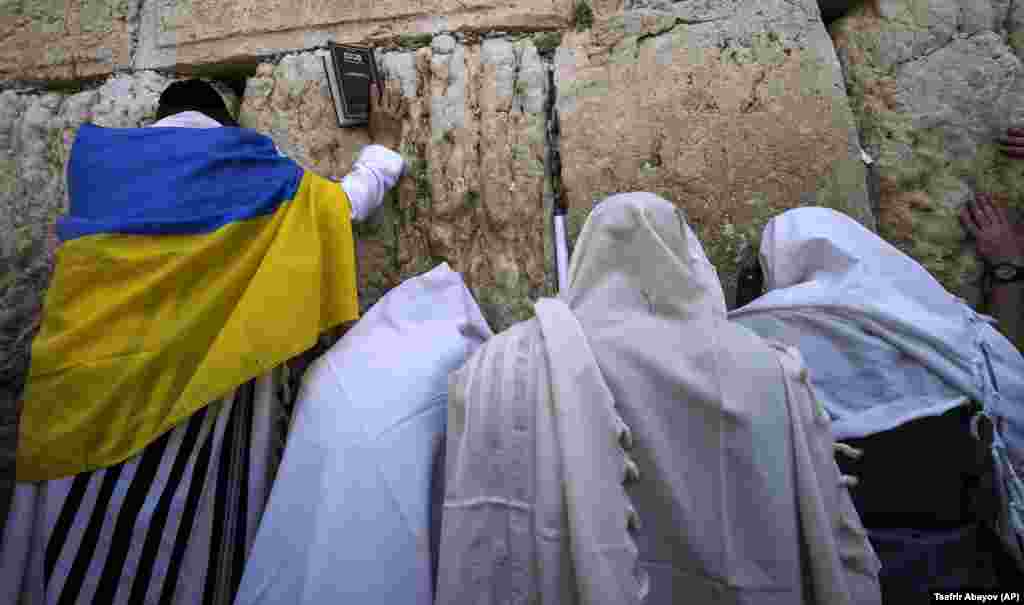 An ultra-Orthodox Jewish man wrapped in a Ukrainian flag is seen during the Jewish holiday of Passover at the Western Wall in Jerusalem&#39;s Old City.