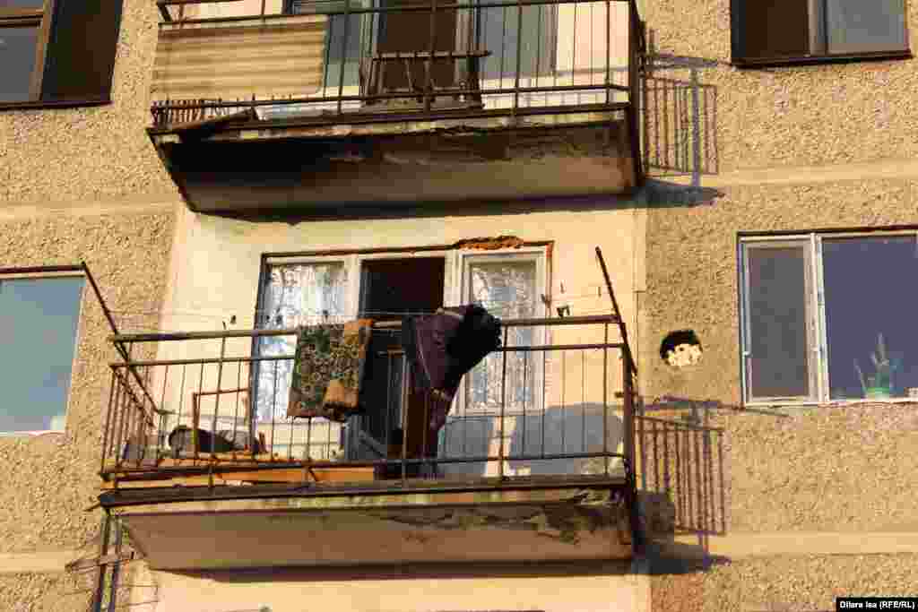 Ребенок на балконе многоэтажки, в которой часть квартир остается пустующей.