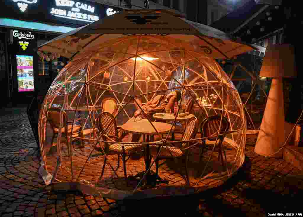 A man sleeps inside a protection bubble used by a pub for its customers as part of coronavirus social-distancing measures during a newly instated curfew in Bucharest. The Romanian government imposed the 30-day nationwide curfew starting on November 9, with people&#39;s movements prohibited between 11 p.m. and 5 a.m. (AFP/Daniel Mihailescu)