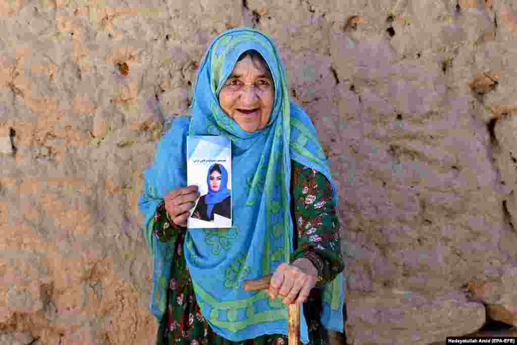 An Afghan woman holds a poster of Afghan journalist Saleha Soadat, candidate for the parliamentary elections, and poses for a photograph in an internal displacement camp in the outskirt of Kabul on October 11. (EPA-EFE/Hedayatullah Amid)