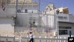 A Syrian policeman walks in front of the damaged U.S. Embassy compound on July 11 after pro-government protesters stormed the facilities in Damascus.