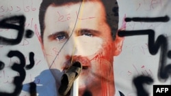 Një poster i dëmtuar i presidentit të Sirisë, Bashar Al Asad, në Allepo