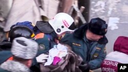 Спасатели несут найденного под обломками дома живого ребенка, 1 января 2019 года