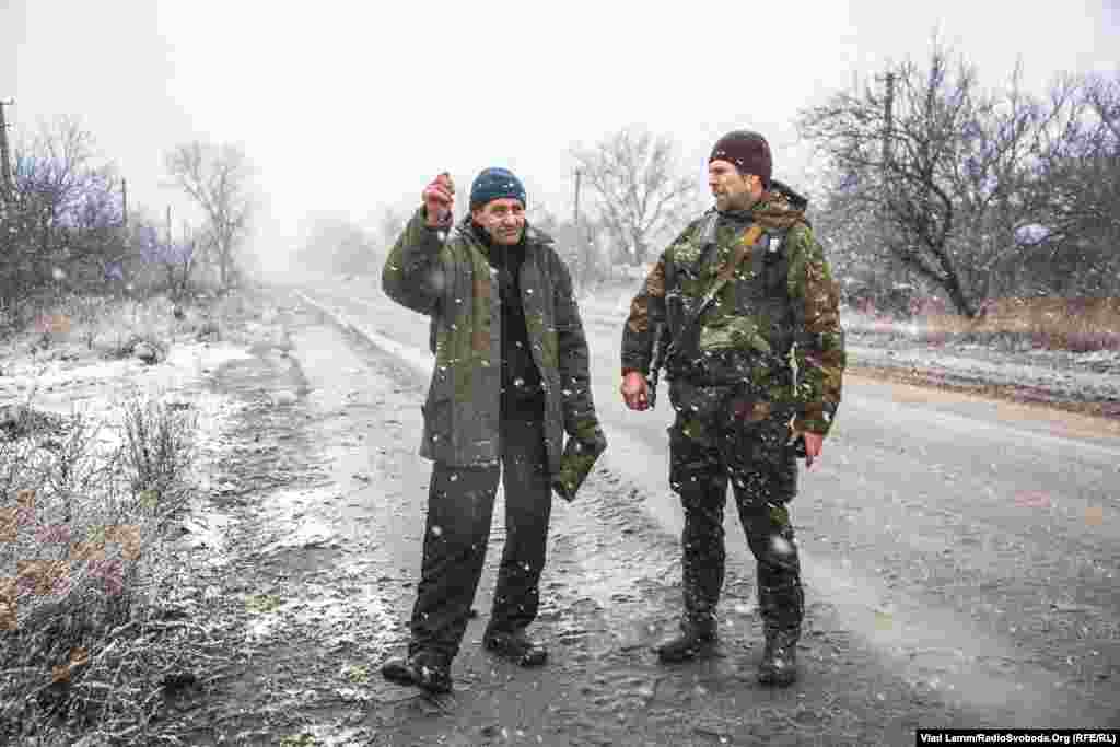 Украинский военнослужащий с позывным &quot;Митяй&quot; беседует с местным жителем Валентином Ивановичем. Валентин Иванович, который живет в наиболее разрушенной части села Первомайское, рассказал об отсутствии информации с &quot;материковой&quot; Украины (в селе показывают только российские телеканалы)