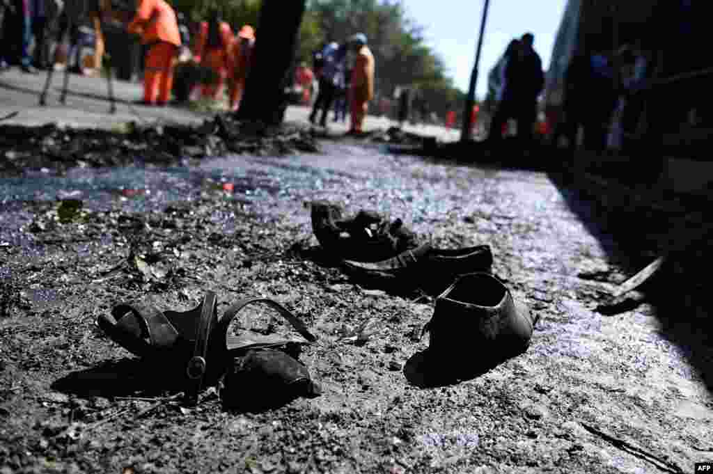 The shoes of victims are seen on the ground as Afghan residents inspect the site of a car-bomb attack in western Kabul on July 24. At least 24 people were killed and 42 wounded. (AFP/Wakil Kohsar)