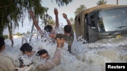 Residents evacuting through floodwaters dodge an army truck carrying relief supplies for flood victims in Pakistan's Muzaffargarh district of Punjab Province on August 11.