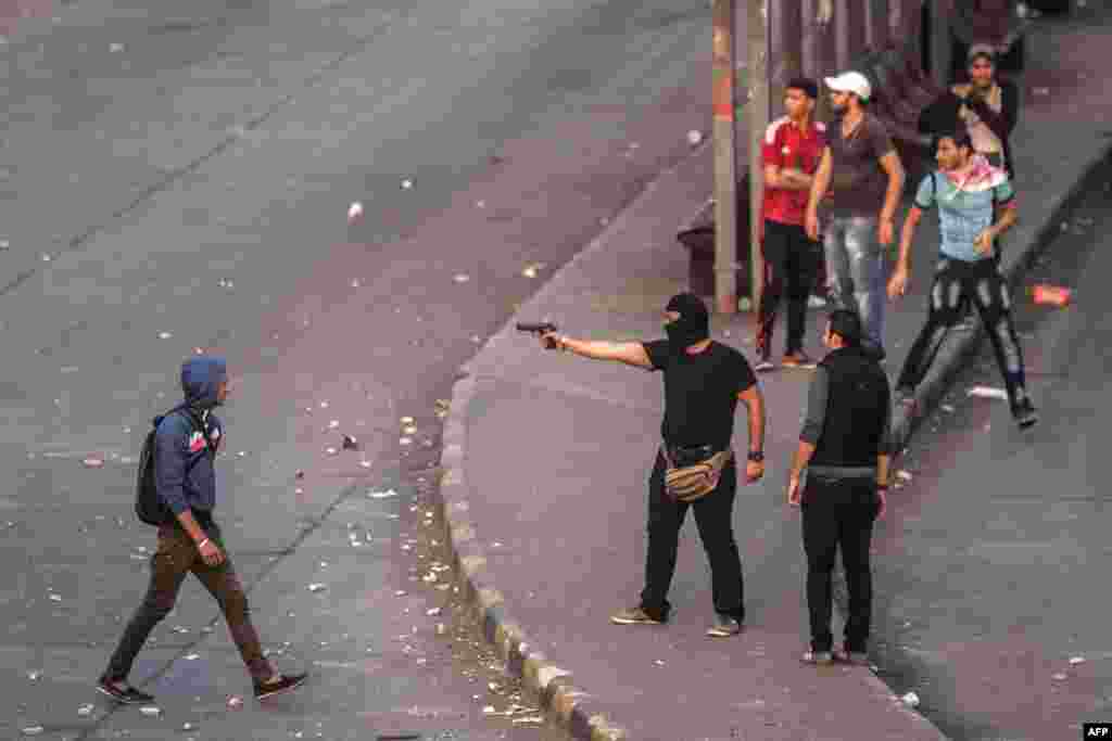 A masked man in Cairo aims his gun as he stands among fellow antimilitary demonstrators on November 19 marking the anniversary of protests in 2011 that ignited deadly clashes with security forces.&nbsp;(AFP/Mahmoud Khaled)