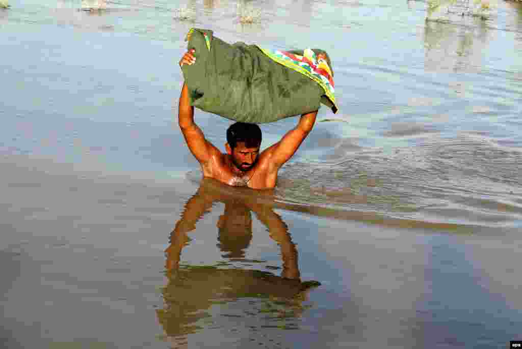 A Pakistani carrying his possessions wades through floodwater in the area of Larkana. According to Pakistani officials, the death toll from three weeks of floods has reached 118. (epa/Waqar Hussein)