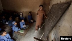 A man teaches students at a school in Kababiyan refugee camp in Peshawar, Pakistan, on October 6.