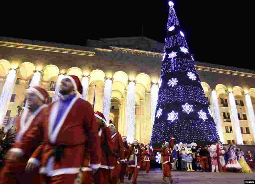 Revellers dressed as Santa Claus enjoy a seasonal celebration near a New Year&#39;s tree in front of the Georgian parliament building in Tbilisi on December 25. (Reuters/David Mdzinarishvili)