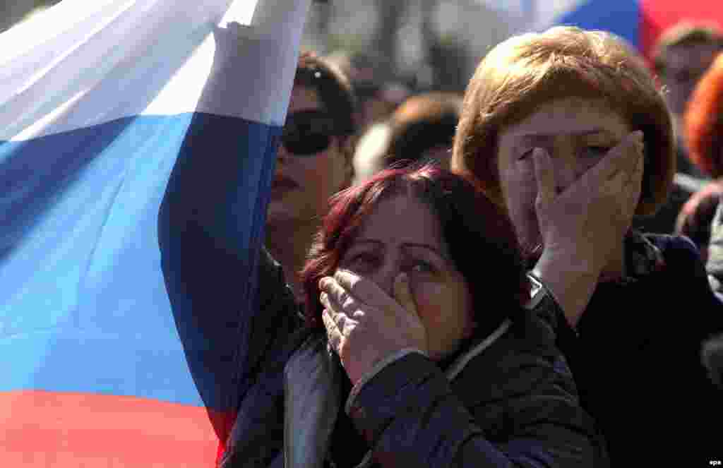 Ukraine -- People react as they watch a televized speech of Russian President Vladimir Putin on a screen in central Sevastopol, Crimea, March 18, 2014