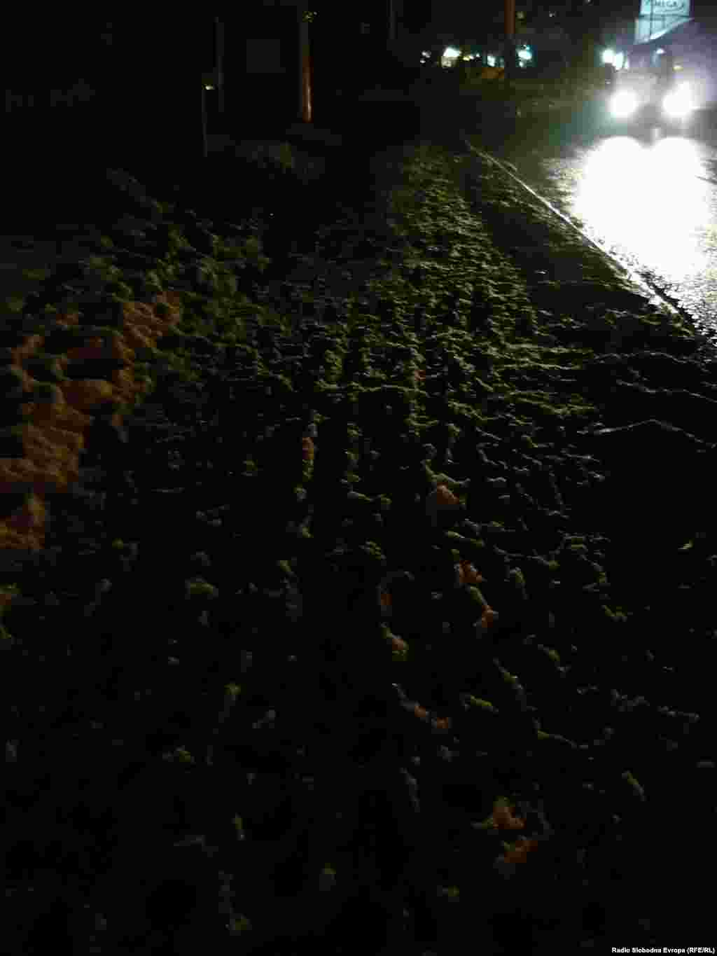 дел од тротоарите кои не се исчистени од снегот и мразот се осветлени само од автомобилите